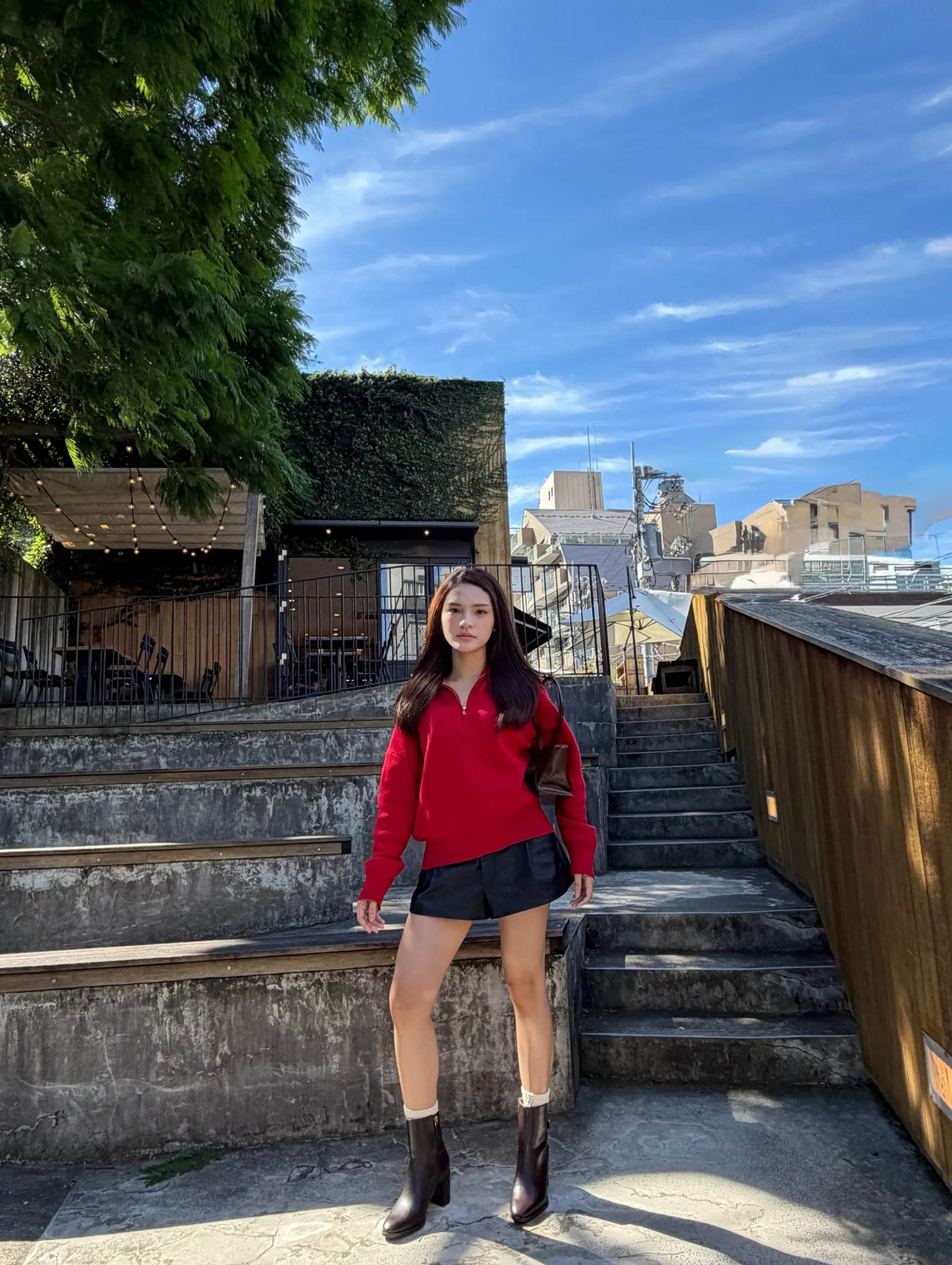 Outfit of a red quarter-zip sweater, black relaxed shorts, and dark brown knee-high boots with light cuffs.