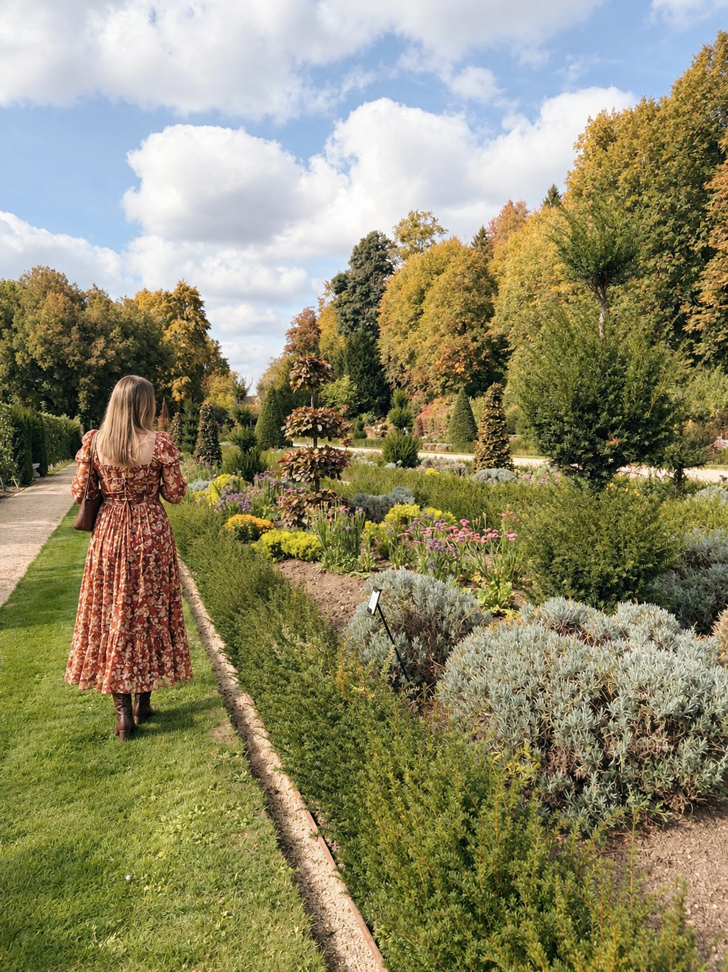 Woman in a rust-red floral maxi dress with puffed sleeves, dark ankle boots, and a small shoulder bag.