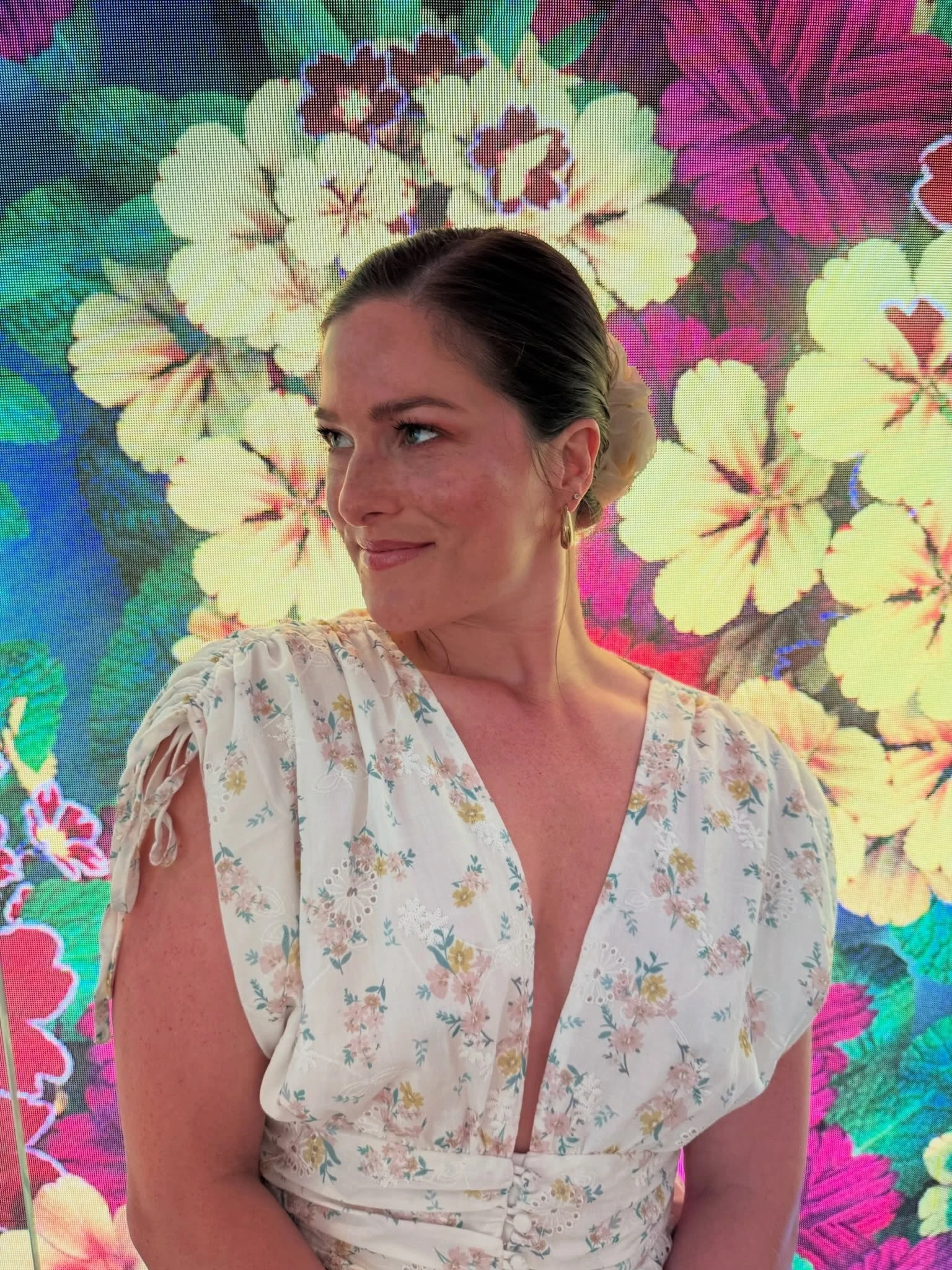 Woman wearing a white floral dress with a deep V-neckline in a vacation setting.