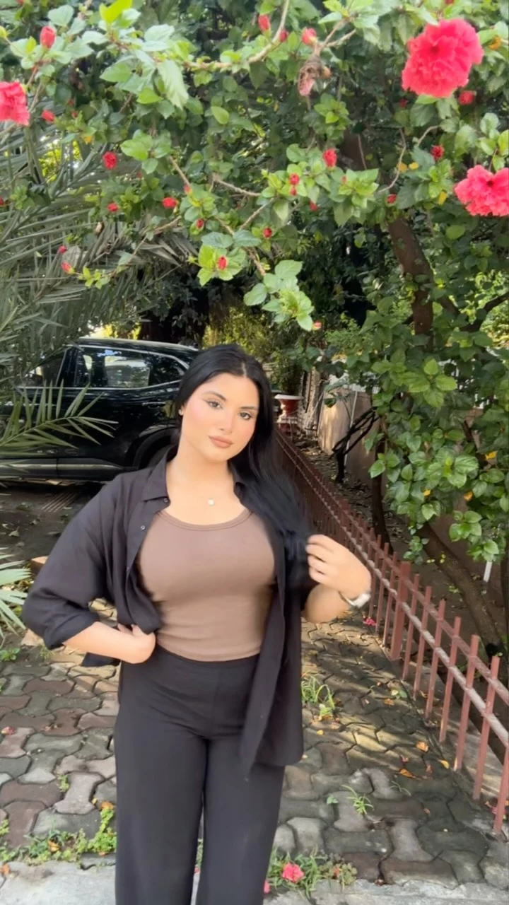 Woman wearing a brown fitted tank, open black long-sleeve shirt, and black wide-leg trousers.