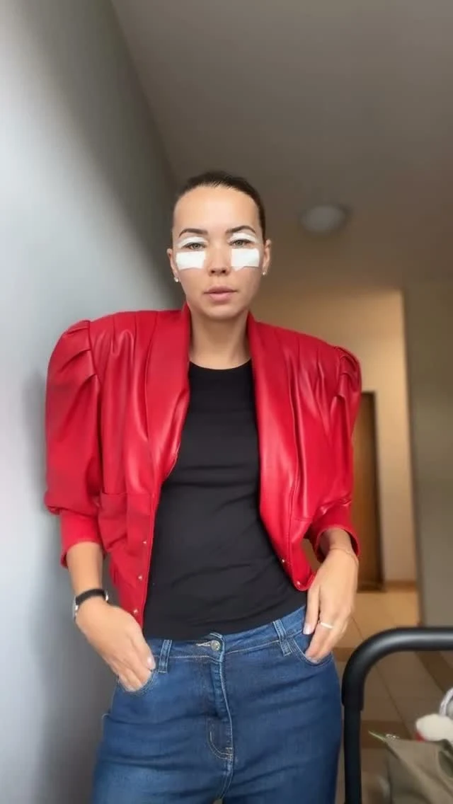 Vibrant red cropped leather jacket with puff shoulders styled over a black top and high-waisted blue jeans.