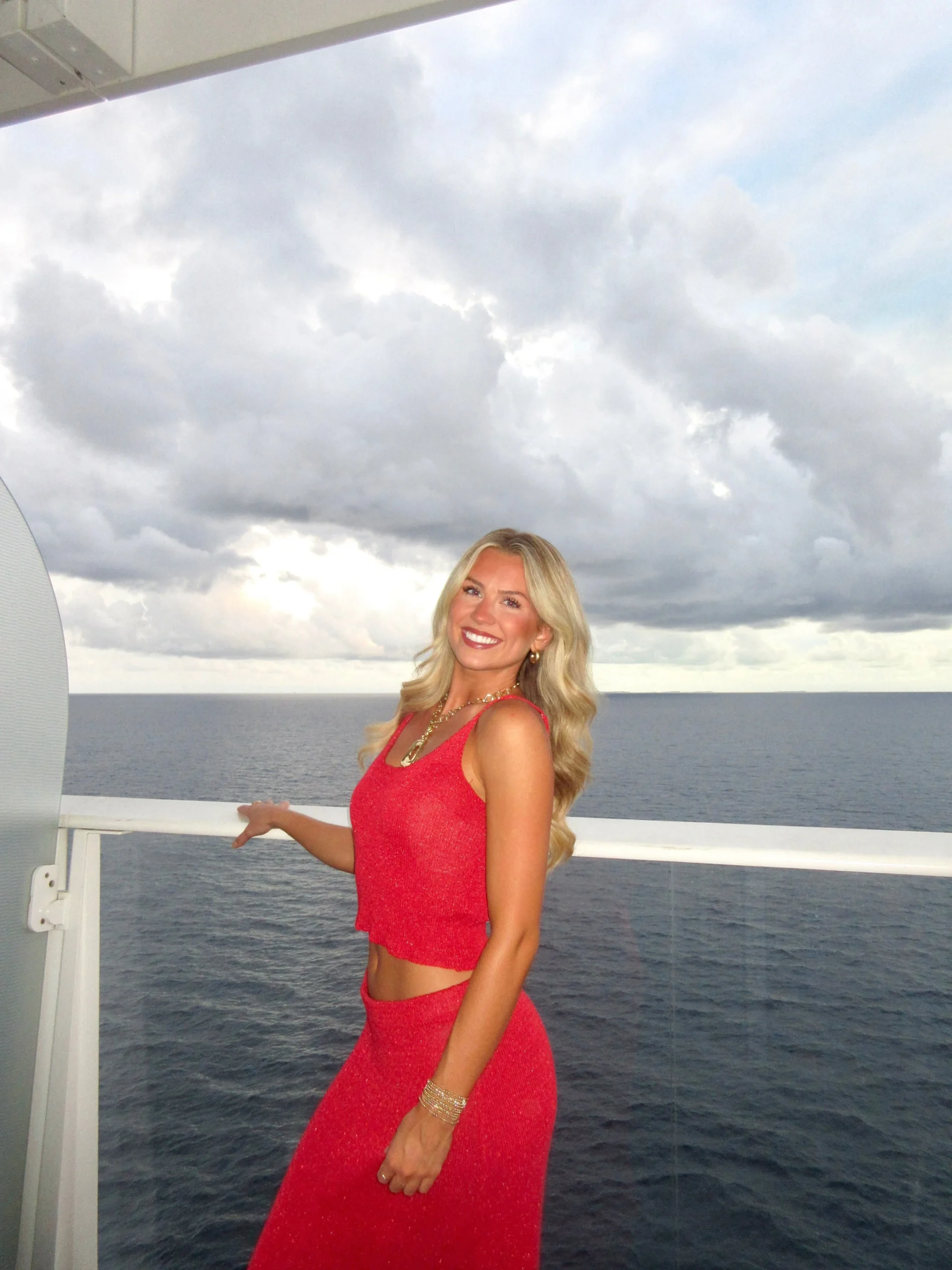 Woman wearing a matching bright red knit crop top and long skirt with gold jewelry.