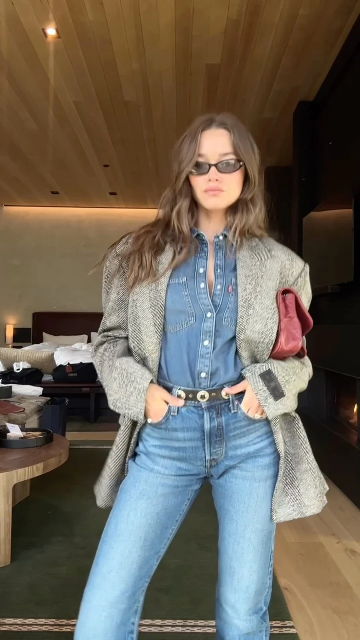 Woman wearing a denim shirt, herringbone blazer, wide-leg jeans, and dark blue cowboy boots.