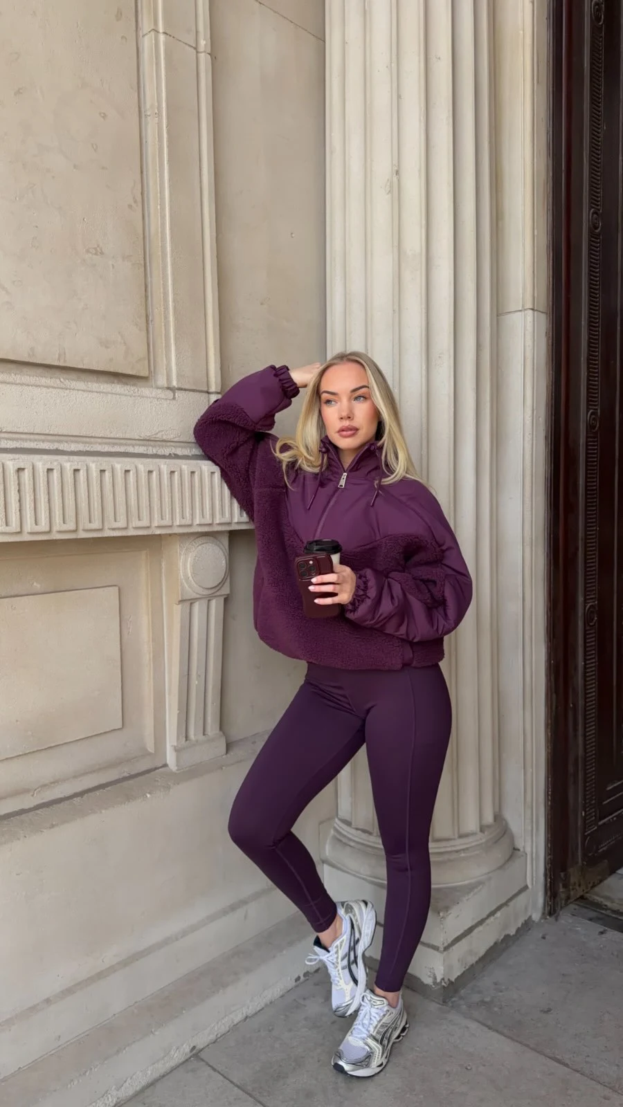 Person wearing a matching deep plum hooded jacket and leggings with gray and white sneakers.