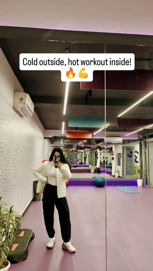 Mirror selfie of a white quilted puffer jacket, white top, black pants, and pink-accented sneakers.